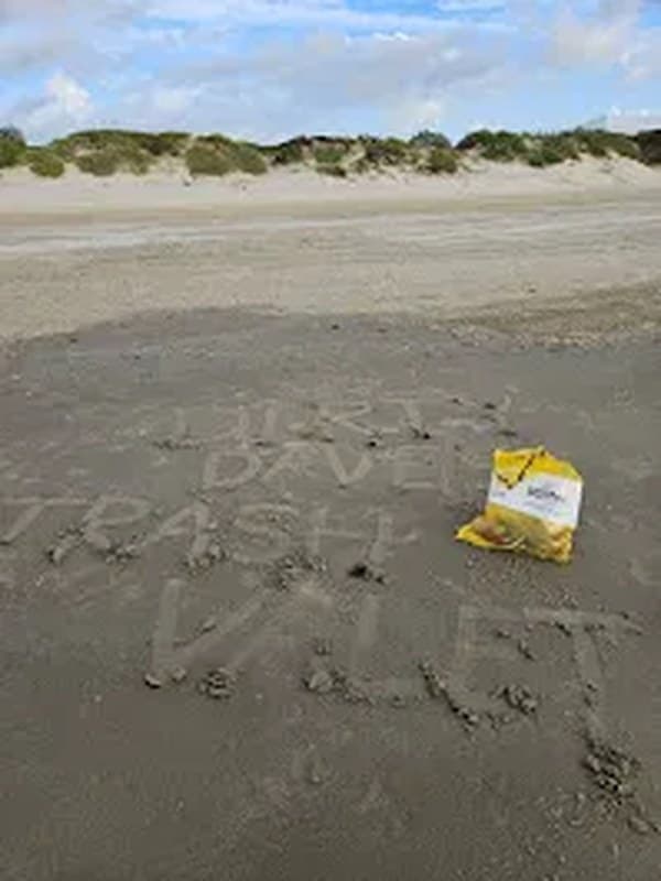 Dirty Dave's Trash Valet written in the sand on a Texas beach